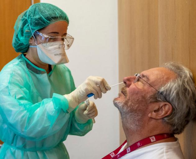 A health technician wearing protective gear takes a swab from a patients nostrils at a Covid-19...