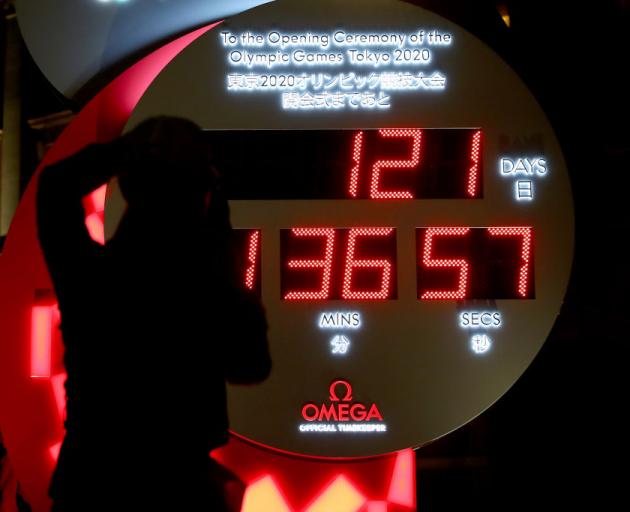 People in Tokyo watch the official Olympic countdown clock with the remaining days and time until the 2020 Summer Olympics after it was announced yesterday that the Games will be postponed until 2021 due to the coronavirus outbreak. Photo: Getty Images