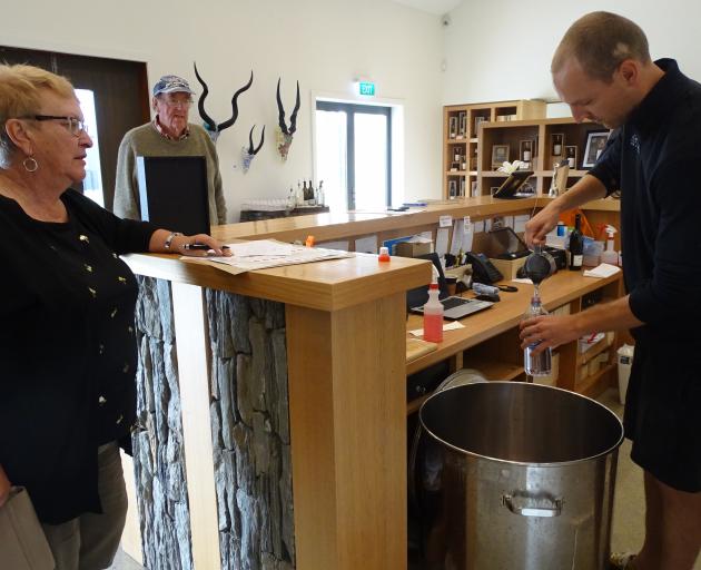 Cardrona Distillery ambassador Sam Bickley pours free alcohol hand sanitiser into a container for...