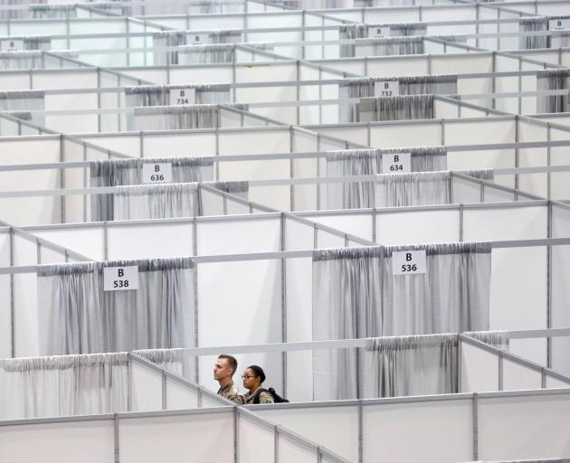 Military personnel walk among cubicles being prepared as part of phase 2 of the Javits New York...