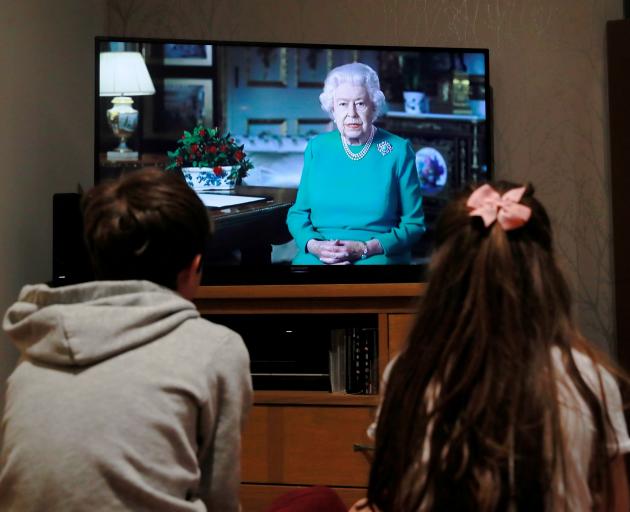 Noah (9) and Milly (7), of Hertford, watch Queen Elizabeth during a televised address to the...