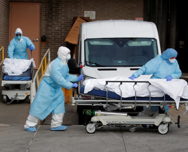 Healthcare workers wheel the bodies of deceased people from the Wyckoff Heights Medical Center...