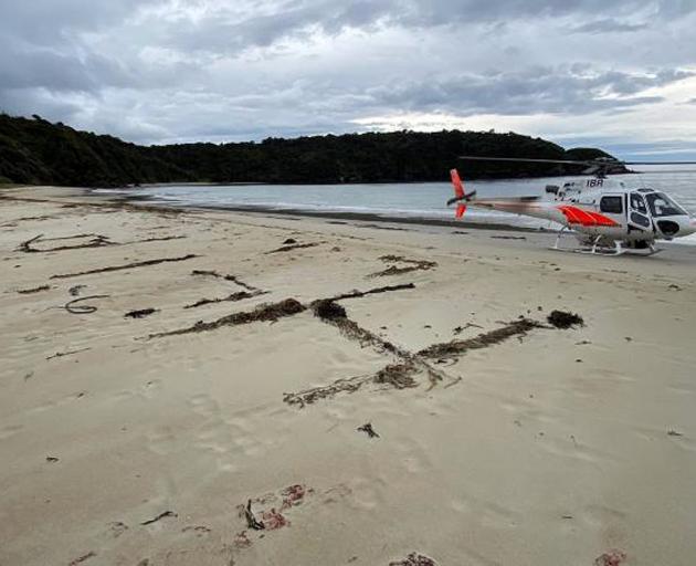 Eli Smith wrote a message in the sand as he waited to be rescued. PHOTO: SUPPLIED

