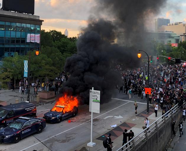 A police car burns near CNN Center in Atlanta, Georgia, as people protest against the death of...