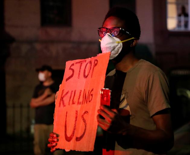 A man wearing a protective face mask holds a sign during a protest in the Brooklyn borough of New...