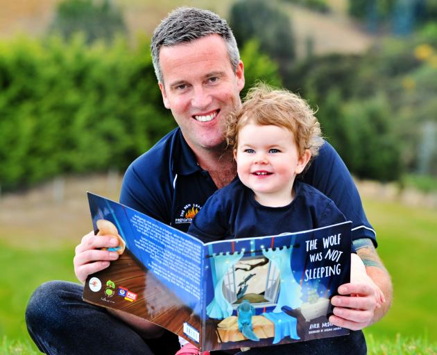 Dunedin firefighter Kris Kennett reads a copy of the book The Wolf Was Not Sleeping to his...