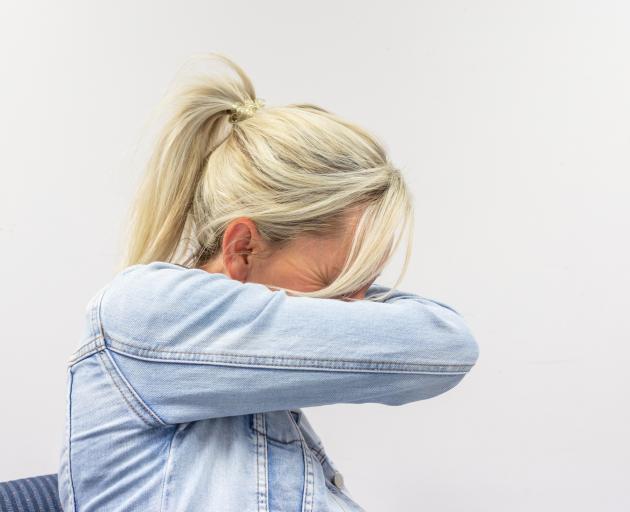 A woman sneezes into her jacket. Photo: Getty Images