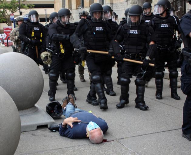 Martin Guginolays on the ground after he was shoved by two police officers. Photo: Jamie King via...