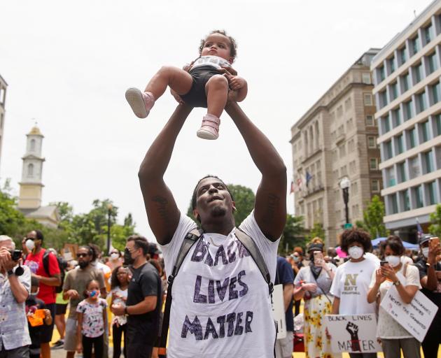A demonstrator holds up a child during a protest against racial inequality in Washington. Photo:...