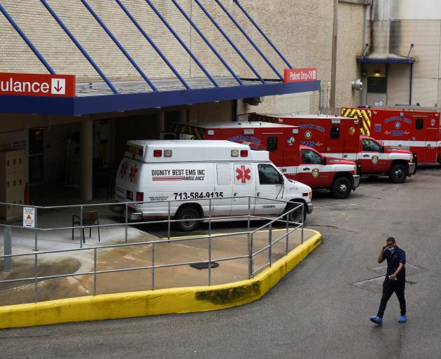 A medical worker walks past a row of ambulances parked outside of Houston Methodist Hospital as storm clouds gather over the Texas Medical Centre. Photo: Reuters