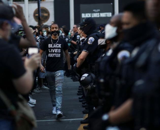 A demonstrator walks past police officers near Black Lives Matter Plaza in Washington. PHOTO:...