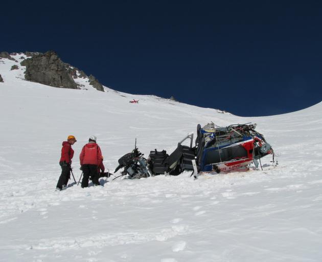 Investigators examine the main fuselage of the helicopter, with the tail section about 300m...