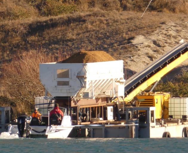 Smooth crossing ... Contractors pilot a barge laden with gravel and equipment across Lake Dunstan...