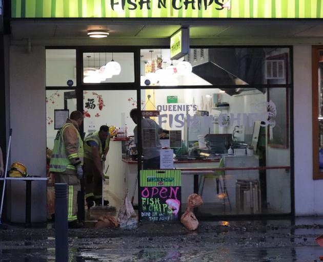Firefighters help remove water from a Camp St shop. PHOTO: HUGH COLLINS