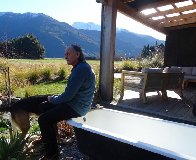 Wild Earth Lodge host Pete Phillips with his dog Cash, sitting on the bath on the veranda of ‘...