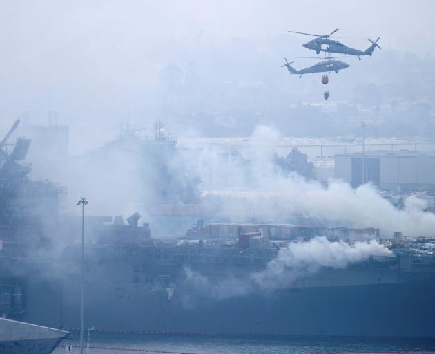 US Navy helicopters and city firefighters continue fighting a fire on the amphibious assault ship USS Bonhomme Richard. Photo: Reuters