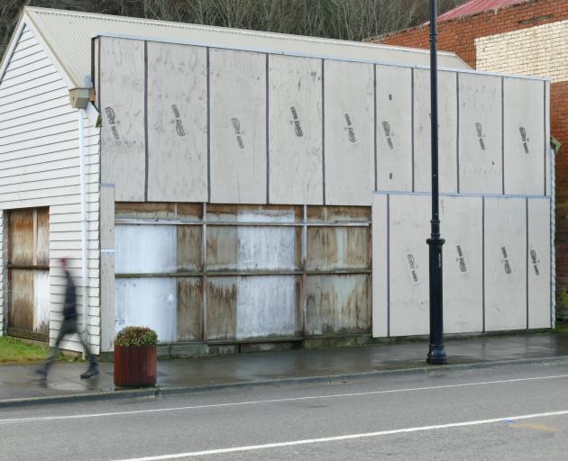 A pedestrian walks past a boarded-up shop in Lawrence's main street on Wednesday; refurbishment...