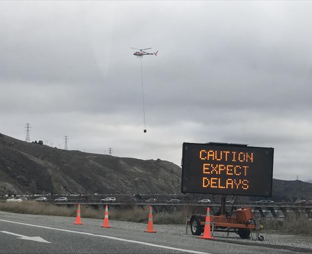 Cars line up on Deadman's Point Bridge just outside of Cromwell as a helicopter goes to work on the slip. Photo: Daisy Hudson