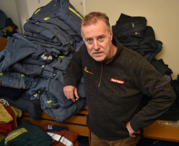 Paul Harrington surrounded by uniforms his dry-cleaning company cleans for New Zealand Aluminium...