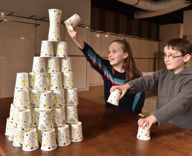 Kyla Rae (9) and her brother Toby (8) try to add to a structure they have built from paper cups...