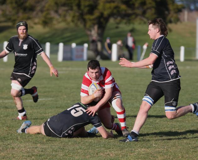 Clutha captain Max Pennell is tackled by Clinton’s fullback Ross Burnet as other Clinton...