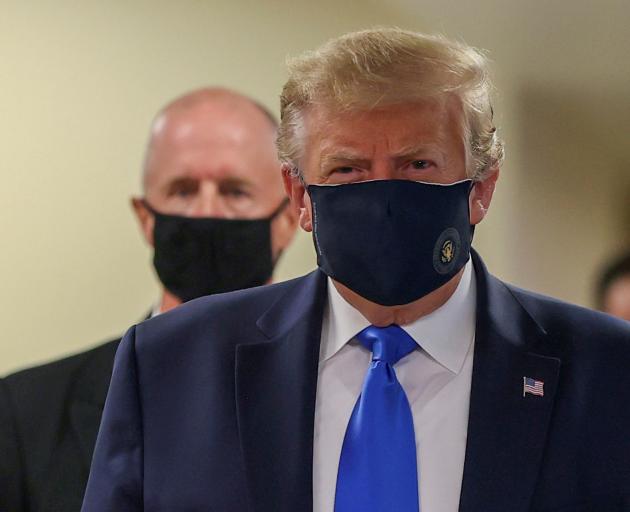 US President Donald Trump wears a mask while visiting Walter Reed National Military Medical...