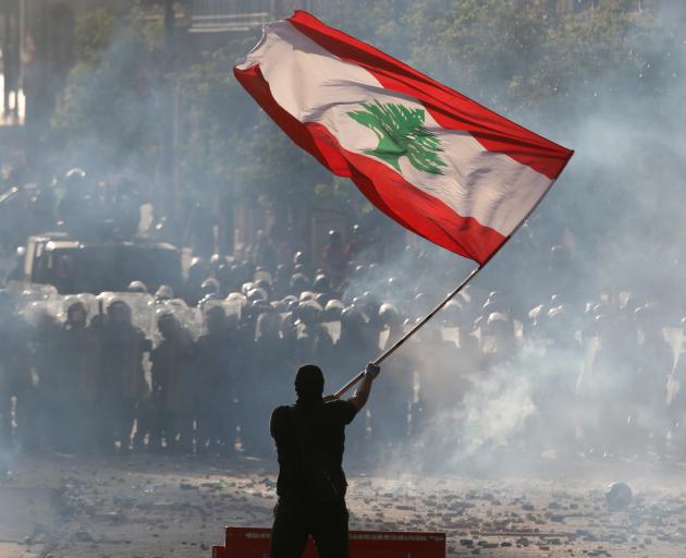 A demonstrator waves the Lebanese flag in front of riot police during the protest in Beirut....