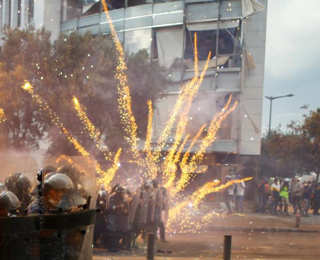 Fireworks are set off in front of police officers during anti-government protests that have been ignited by a massive explosion in Beirut. Photo: Reuters