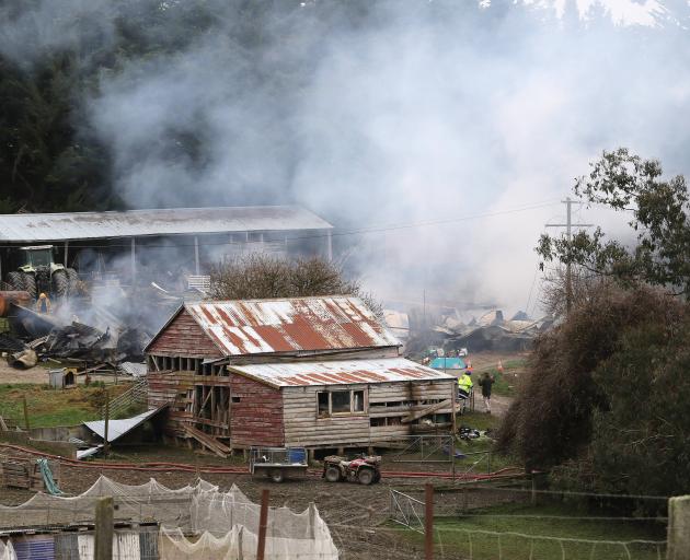 Fire crews assess the damage and dampen down the remains of a large shed that was destroyed by a...