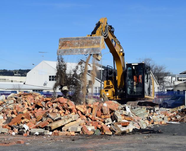 A contractor on Friday shifts rubble with an excavator to clear a site for a new 24-hour gym to...