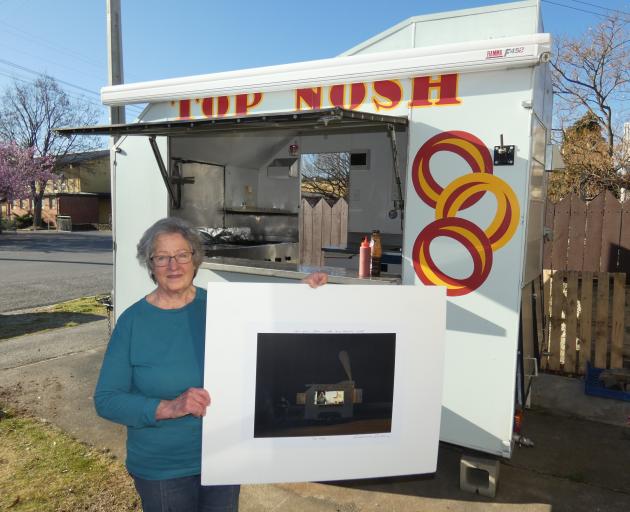 Jean Bonsor in her Top Nosh food trailer holds a signed copy of Grahame Sydney’s eponymous work....