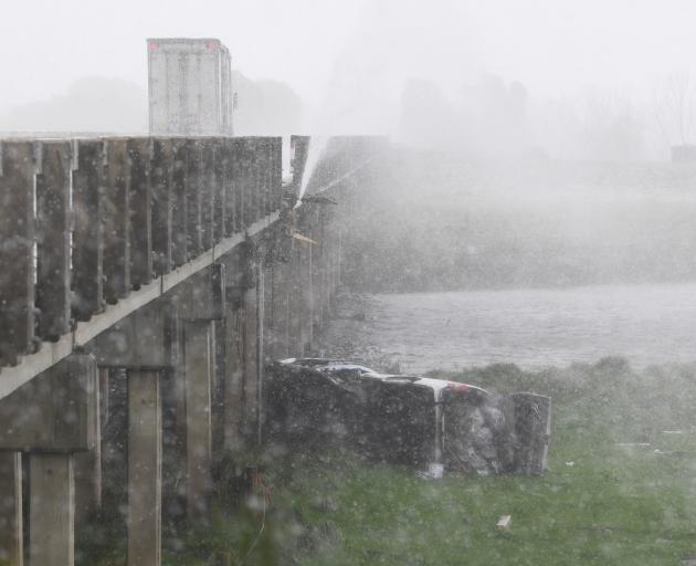 A vehicle lies on its side after crashing into the bridge this morning. Photo: Stephen Jaquiery