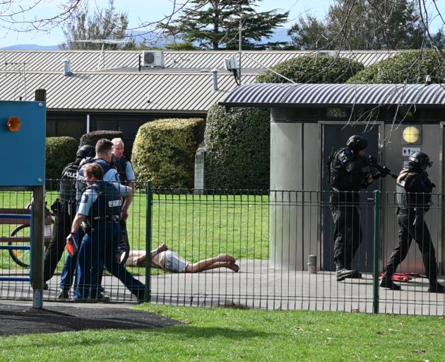 A man lies on the ground as the police AOS squad examine the scene. Photo: Craig Baxter