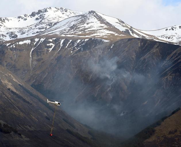 A helicopter heading to fight the Ohau fire passes a burnt-out gully on Monday. Researchers say...