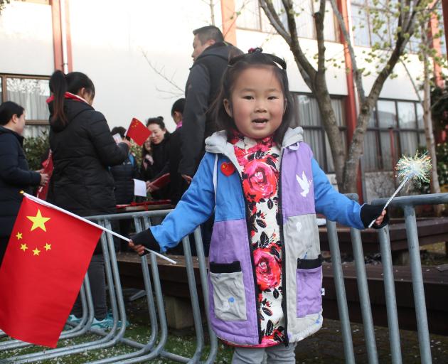 Nancy Wu (4) waves the Chinese flag during a celebration of the 71st anniversary of the founding...