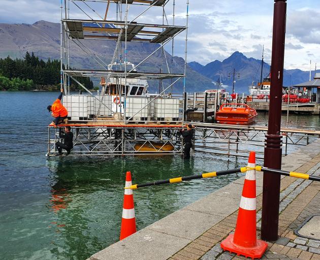 Workers in wetsuits set up a temporary structure at the Queenstown waterfront in 
...