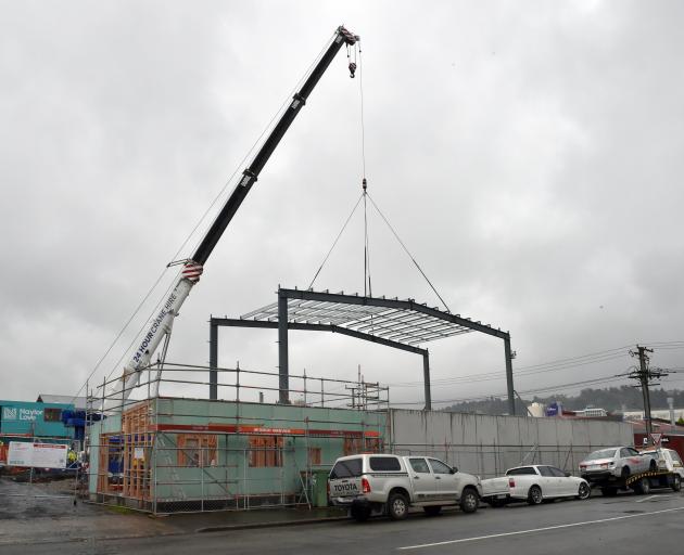 A crane supports a frame in place at a construction site in Ward St, Dunedin. Allied Pickfords...