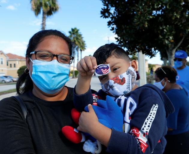 Hazel Martinez holds 4-year-old Leonardo Perez after she voted on Election Day in Poinciana,...