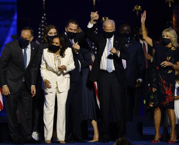 Joe Biden holds up his son Hunter's hand, as they and vice presidential nominee Kamala Harris and...