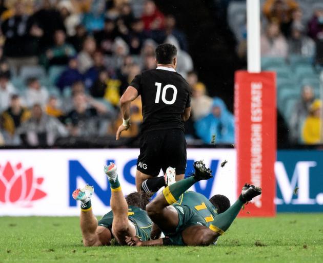 Richie Mo'unga breaks the tackles of Wallabies Michael Hooper and Marika Koroibete in Sydney last...