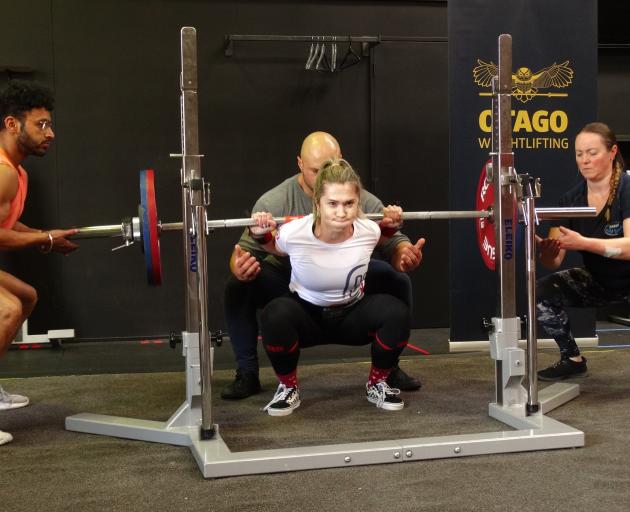 Jess Reid, of Invercargill, successfully squats 125kg while ‘‘spotting’’ are (from left) Sid...