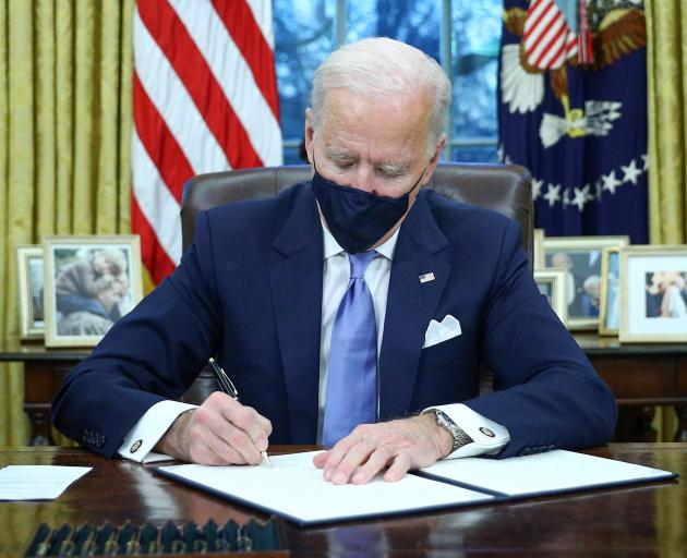 New US President Joe Biden signs executive orders in the Oval Office of the White House after his...