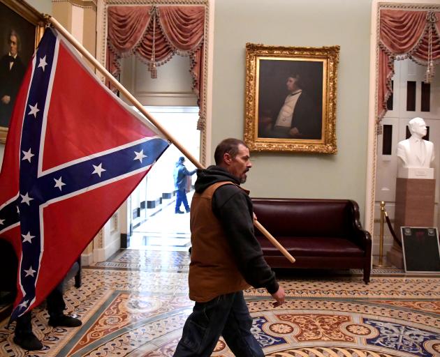 A supporter of President Donald Trump carries a Confederate battle flag on the second floor of...