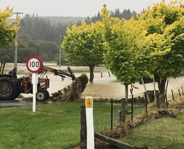 A tractor driver attempts to pull out a debris-covered fence near Pyramid Bridge after floods...