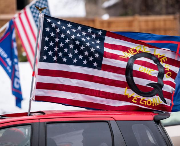 A car with a flag endorsing the QAnon drives by as supporters of President Donald Trump gather...