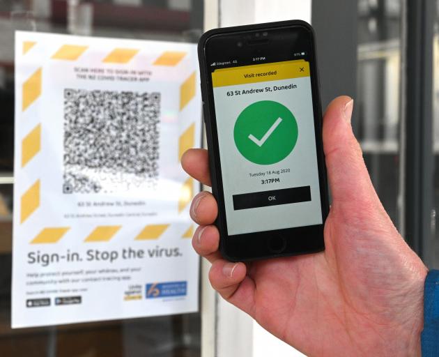 A man uses an app on his phone to scan the Covid-19 tracer QR code at a business in St Andrew St,...