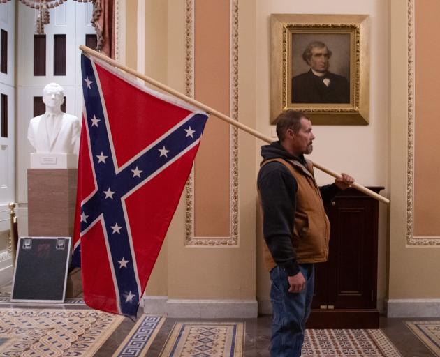 Kevin Seefried, a supporter of US President Donald Trump, holds a Confederate flag outside the...