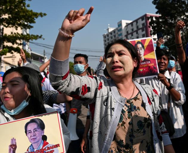 Demonstrators hold placards with the image of Aung San Suu Kyi during a protest against the...