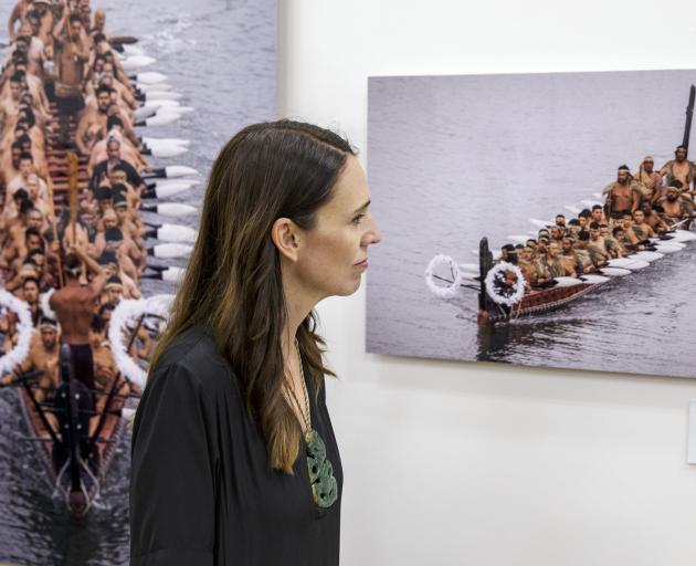 Prime Minister Jacinda Ardern inspects photographs of waka as she visits the He Kaupapa Waka...