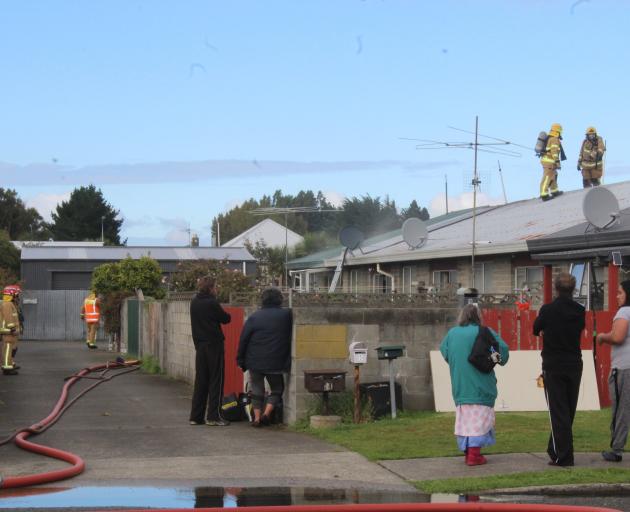 Firefighters work on the roof of an Invercargill flat yesterday to prevent a kitchen fire from...